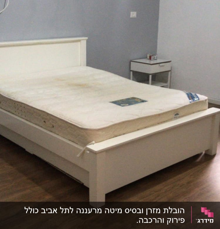 מיטה עם מזרן בחדר ריק על רצפת עץ